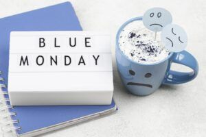 Blue-Monday-high-angle-of-notebook-with-sad-mug-for-blue-monday